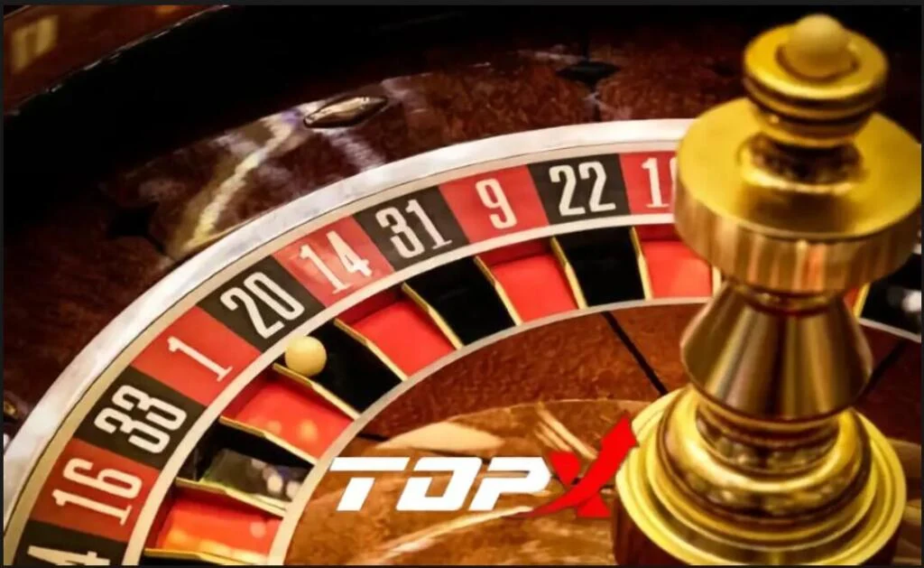 Roda de roleta em close com casas vermelhas e pretas numeradas e o logotipo da TopX sobre a madeira